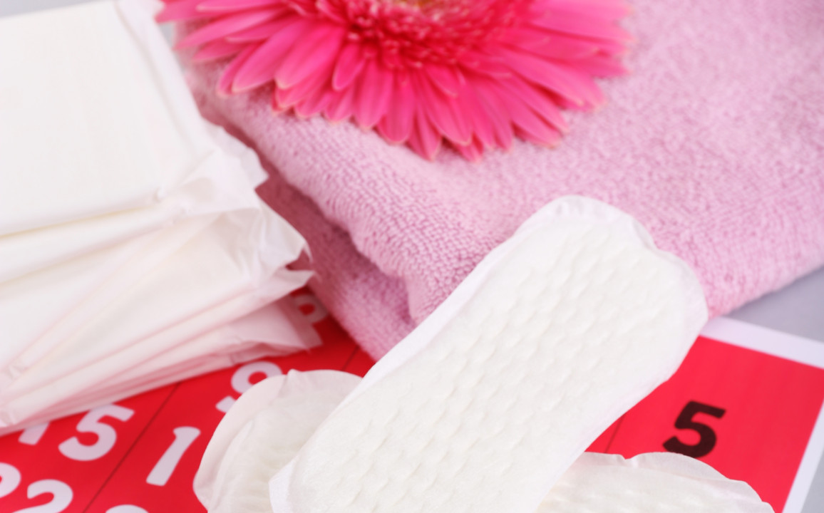 Sanitary pads, calendar, towel and pink flower on light background