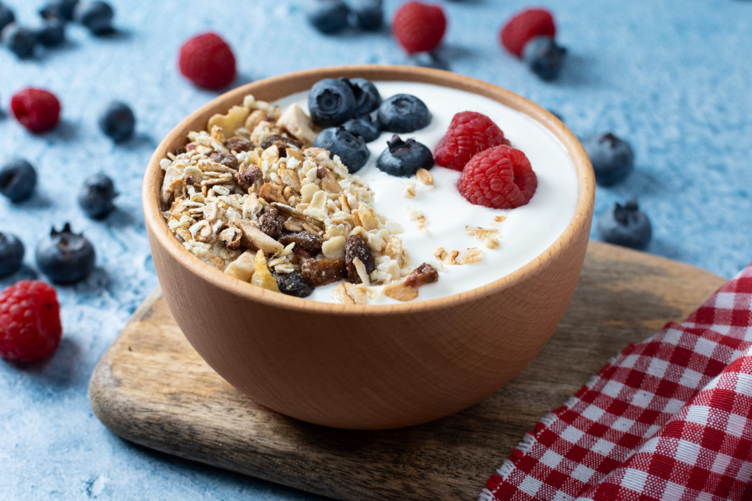 Yogurt with fruit and muesli for breakfast on blue background